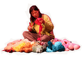 Kristina sits and knits in a nest made of yarn.