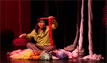 Kristina in yarn nest holds up knitting happily